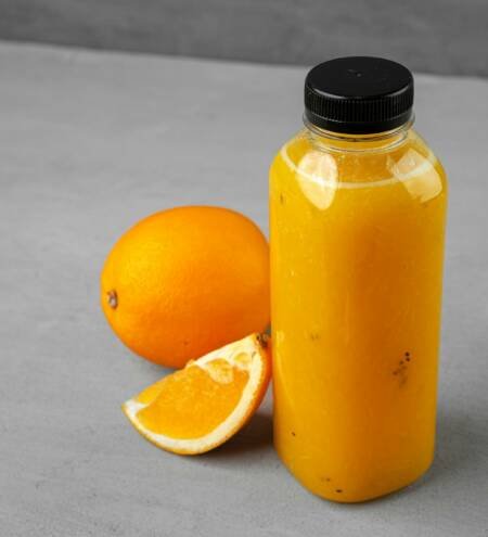 Bottle of freshly squeezed orange juice on gray background