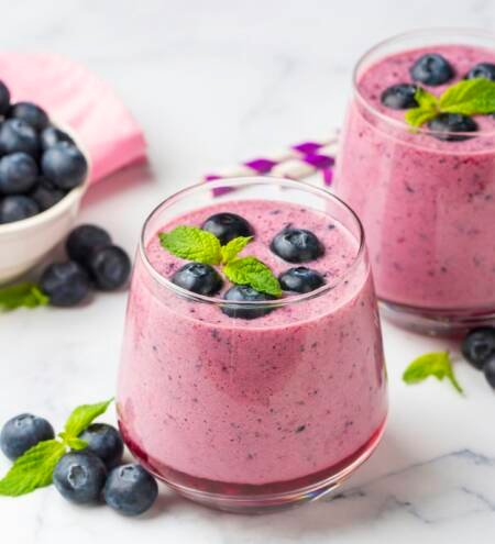 Glass of blueberry smoothie with mint and fresh berries