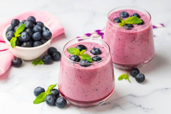 Glass of blueberry smoothie with mint and fresh berries